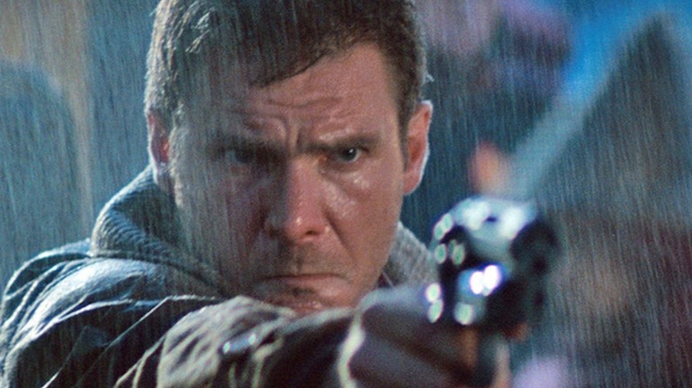Deckard wskazuje pistolet w deszczu